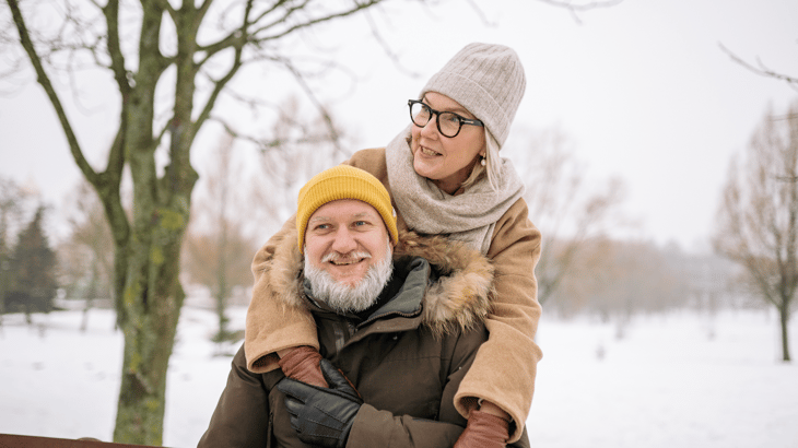 Middle aged couple dressed in cold weather clothes and embracing