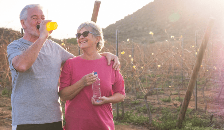 Couple outdoors smiling and stopping for a sip of water