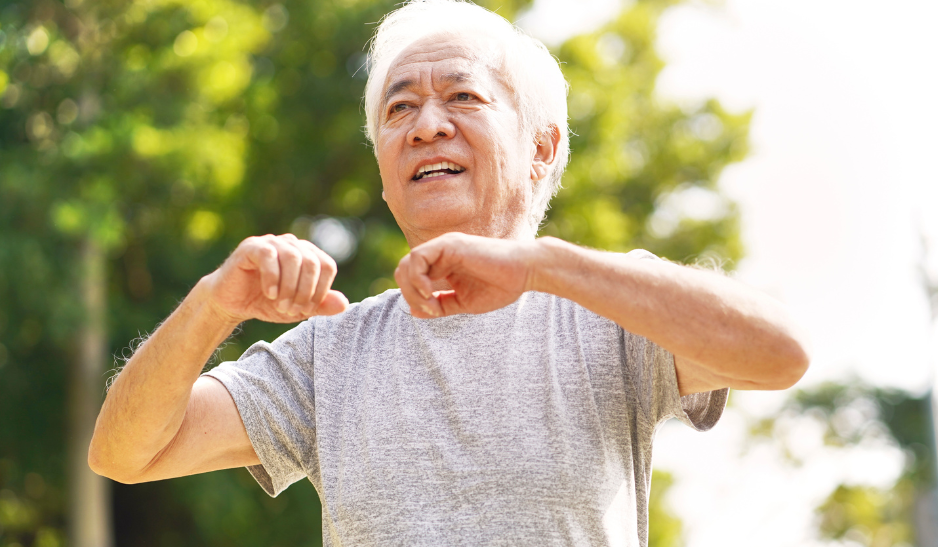 Happy older man doing an aerobic exercise in a sunny park.