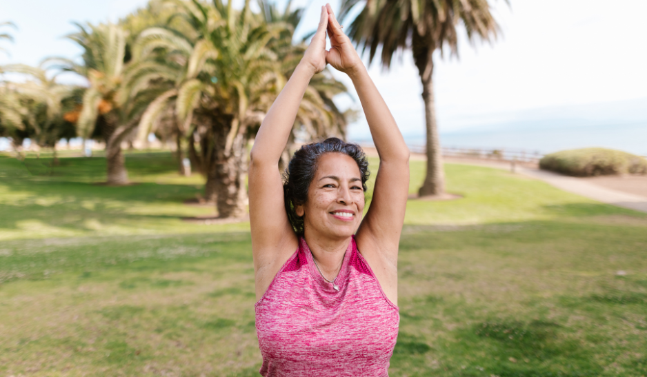 Older woman doing meditative movement outside.